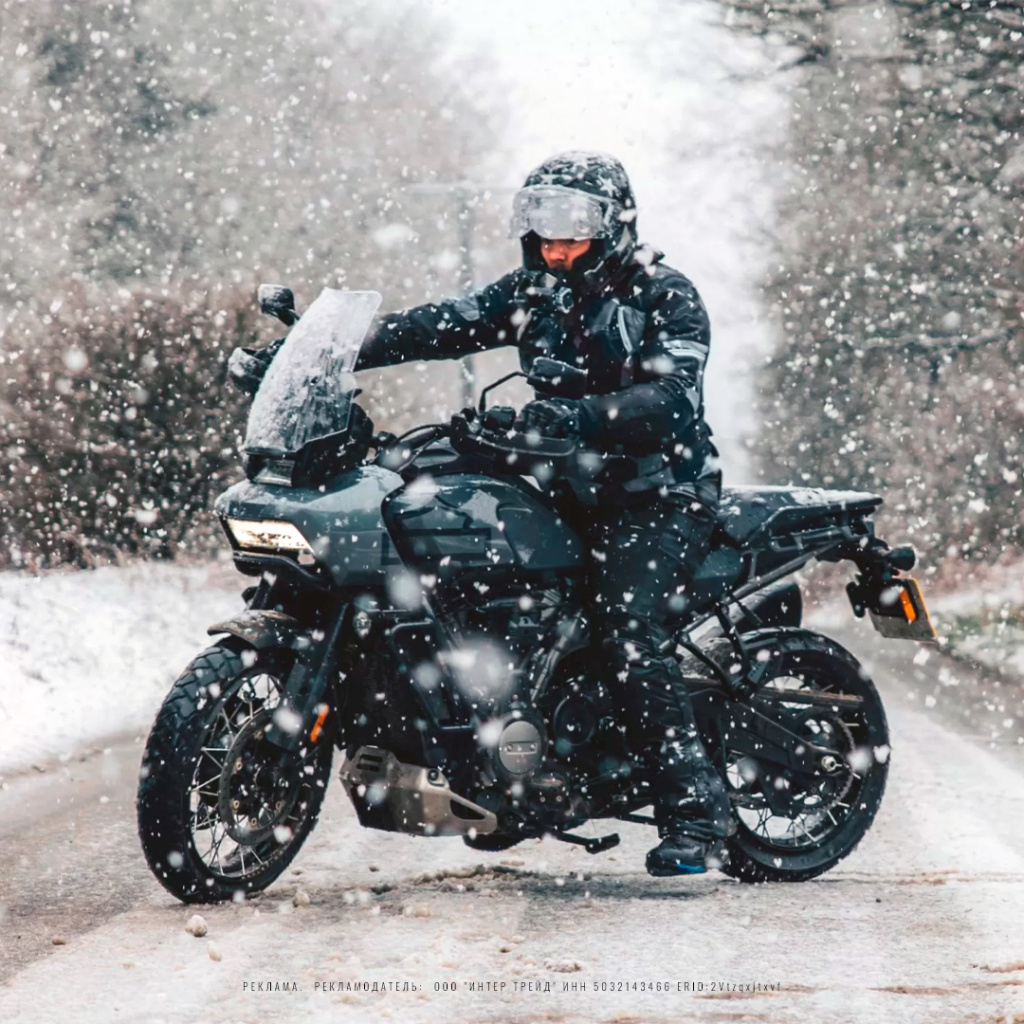 Мотоциклист на мотоцикле в зимней мотокуртке под снегом